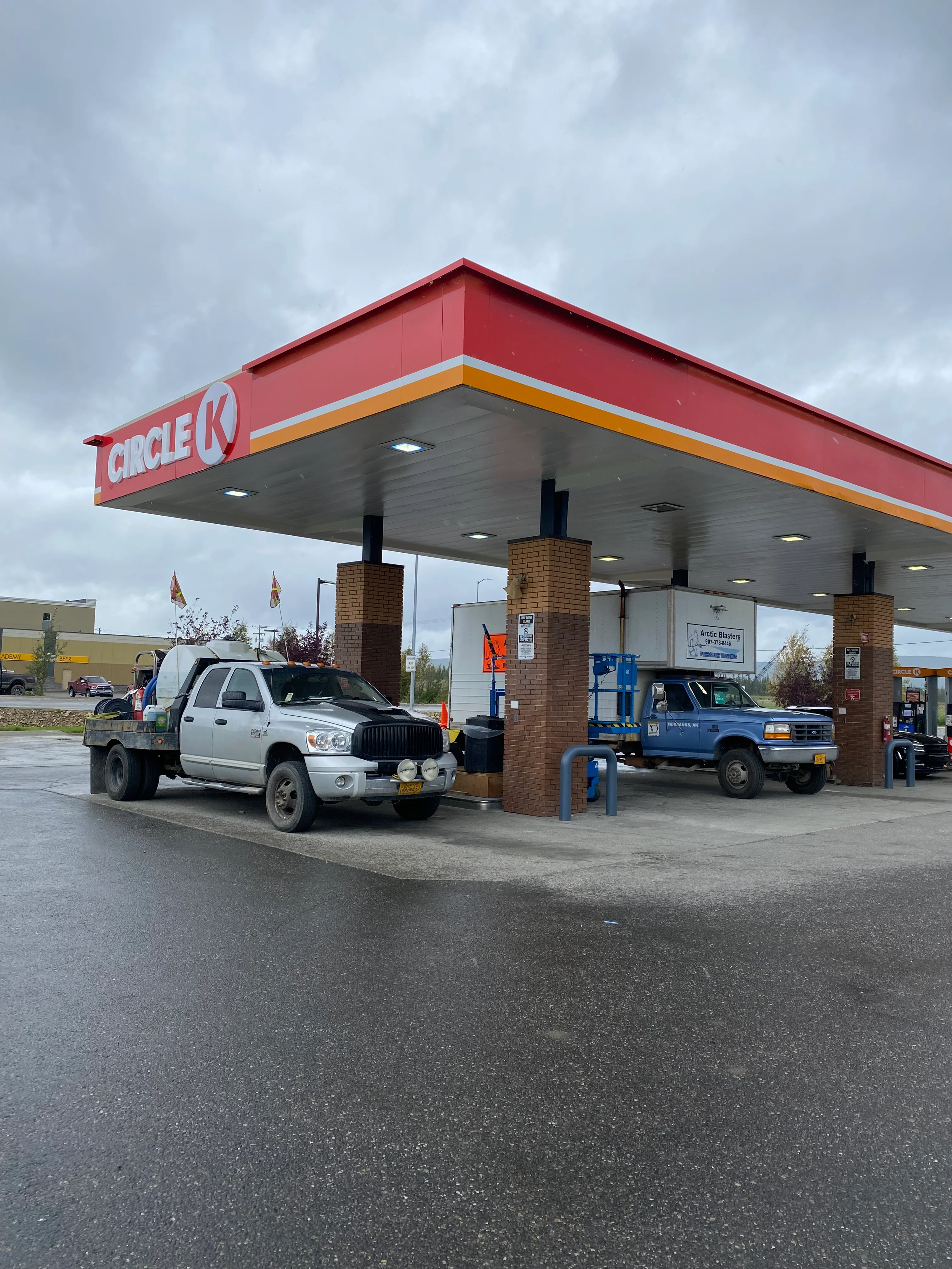 Red and yellow gas station canopy with brick columns after pressure washing, white ceiling and clean concrete surfaces visible