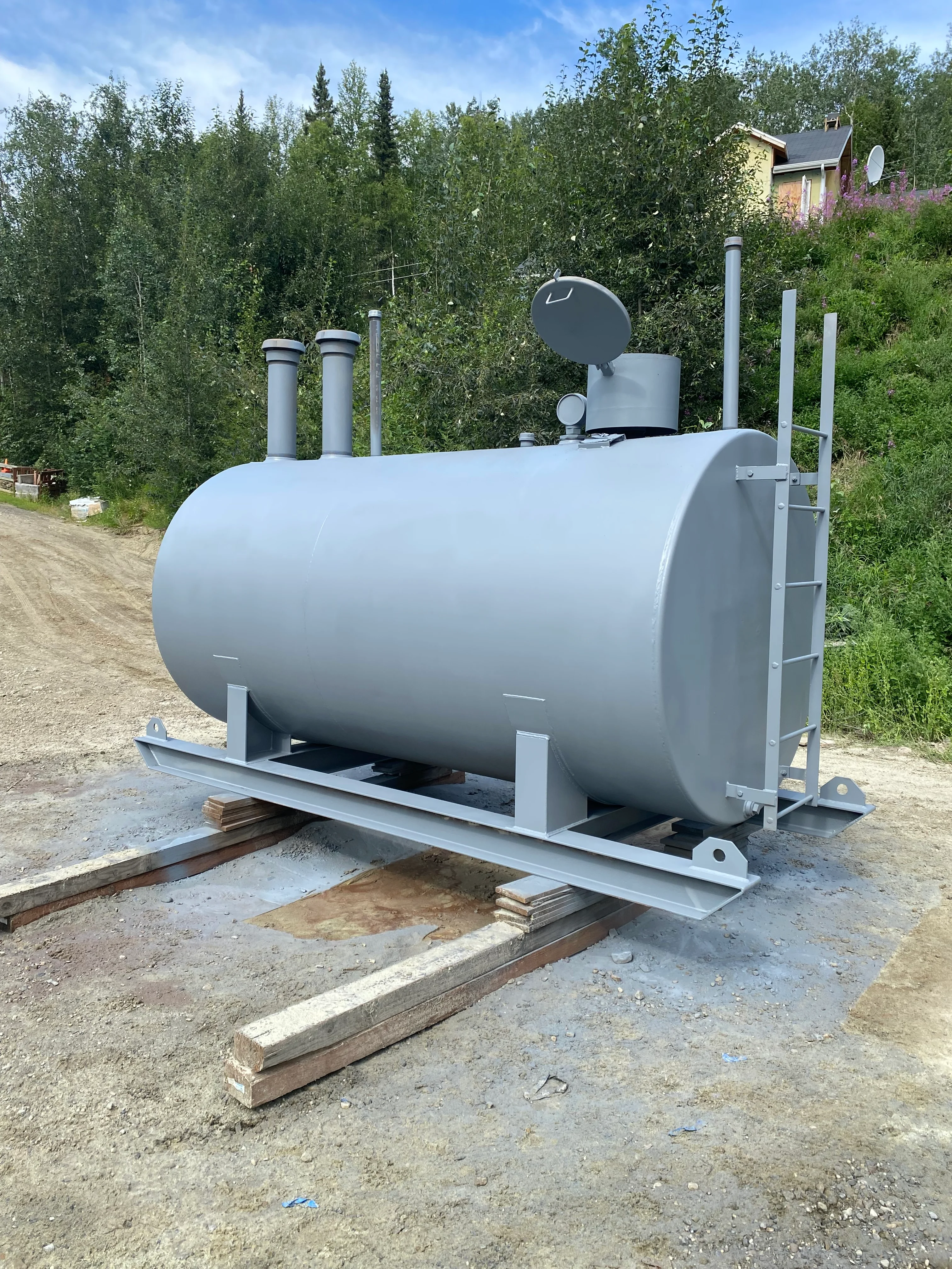 Gray propane tank on steel frame with dual vent pipes and wooden support beams