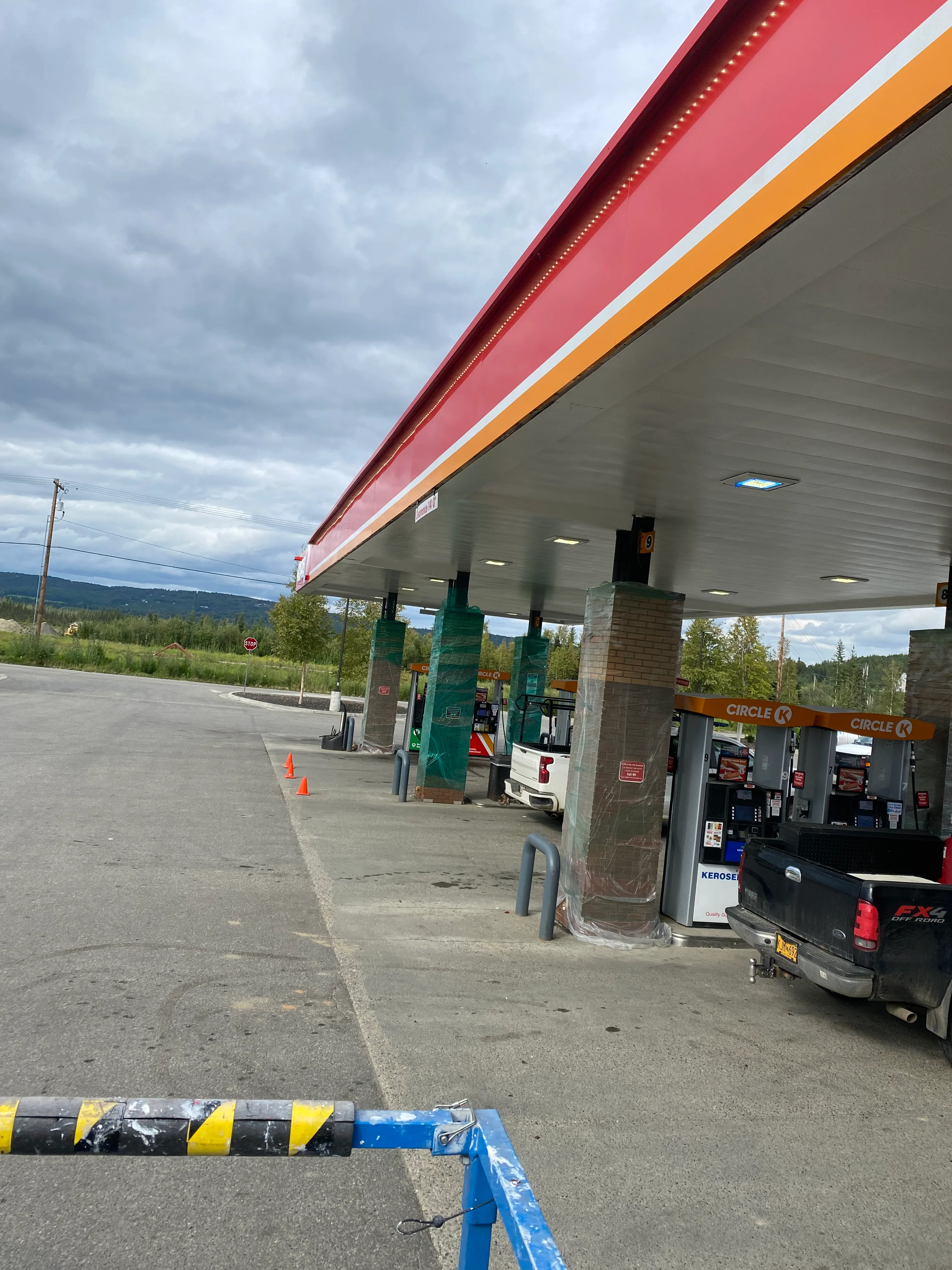 Pressure-washed gas station canopy with red and orange trim, white ceiling, and clean concrete pump island